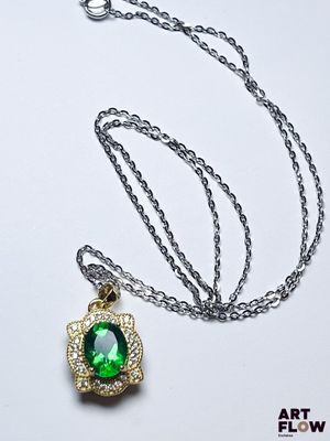 collier composé d'une pierre verte entourée d'une chaîne sur un fond blanc