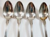 six silver spoons lined up in a row on a white surface