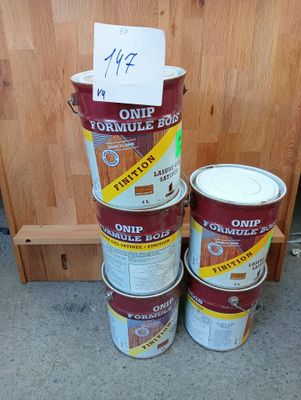 Plusieurs pots de peinture sont empilés les uns sur les autres par terre.