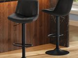 Deux tabourets de bar en cuir noir sont disposés devant le comptoir de la cuisine.