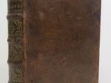 an old brown book with writing on it sitting on a white surface