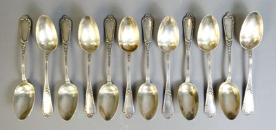 six silver spoons are arranged in a row on a white surface