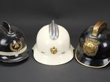 three firemen helmets are lined up on a black surface