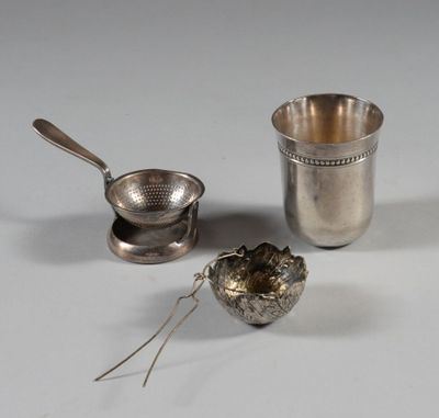 a silver cup with a spoon and a tea strainer