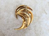 a close up of a gold broochle on a white surface