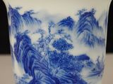 a blue and white vase with a mountain scene on it
