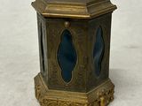 une petite horloge dorée et bleue posée sur une surface blanche