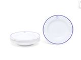 une assiette blanche à bord bleu, à côté d'une pile d'assiettes blanches
