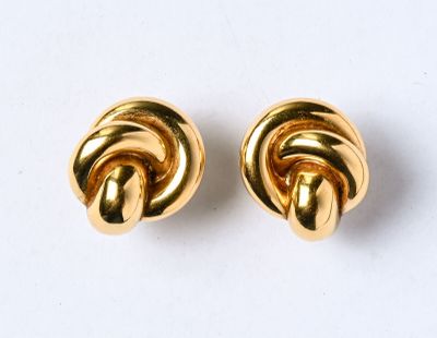 une paire de boucles d'oreilles en forme de nœud, de couleur dorée, posées sur un fond blanc