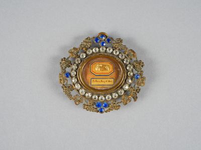 une image représentant une broche bleue et dorée sur laquelle figure un dessin