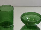 two green glass vases sitting on a white table