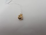 a close up of a gold plated pendant on a white surface
