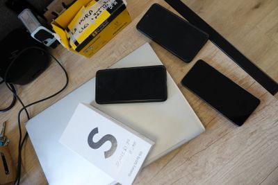 a table with a laptop, cell phone, and other electronics on it