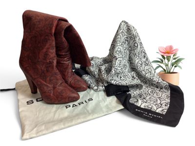 deux paires de bottes et une écharpe posées sur une table, à côté d'une fleur