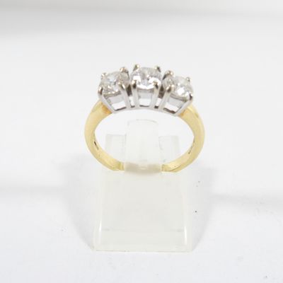 une bague en diamant de trois pierres posée sur un présentoir transparent