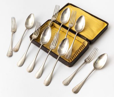 des couverts rangés dans un coffret posé sur une surface blanche, comprenant des fourchettes et des cuillères
