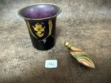 un vase violet et un petit objet en bois posé par terre