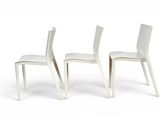 two white chairs sitting next to each other on a white surface