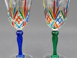 pair of wine glasses with multicolored stems on a gray surface