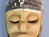 a close up of a wooden mask on a wall