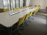 une longue table avec des chaises jaunes et un ordinateur portable posé dessus