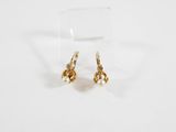 une paire de boucles d'oreilles en or sur une surface blanche