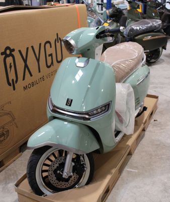 un scooter posé sur une palette devant une boîte