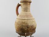 an old vase with a handle on a stand