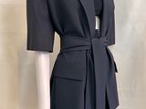 the woman is wearing a black dress and jacket with a belt