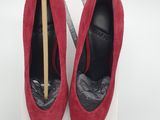 the pair of red shoes are sitting on a box with a wooden stick