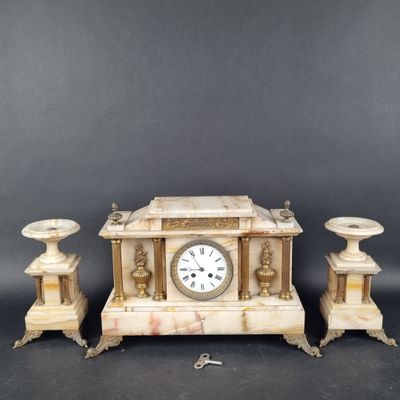 une image représentant une horloge posée sur une table, à côté de deux bougies