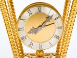 a gold clock with a chain around it on a table