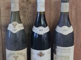 trois bouteilles de vin sont alignées sur une étagère en bois