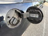 a close up of a car ' s fuel pump with a car in the background