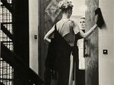 photographie en noir et blanc d'une femme debout devant une porte