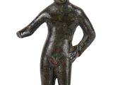 statue d'un homme debout sur un socle en bois, les mains sur les hanches