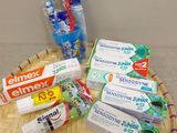 un panier sur lequel sont posés du dentifrice, des brosses à dents et encore du dentifrice