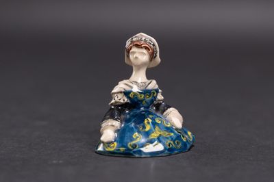 une petite figurine représentant une femme assise sur une table
