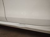 the side of a white car with a hole in the door