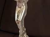 une statue en argent représentant une femme tenant un oiseau, posée sur une table