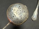 a silver spoon and a silver container on a table