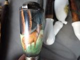 a person holding a vase with a picture of a deer on it