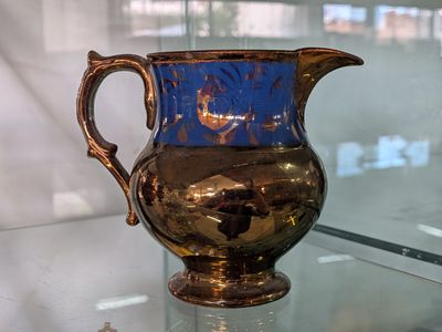 a blue and gold vase sitting on a glass table