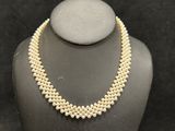 a pearl necklace on a mannequin display with a black background