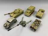 Plusieurs véhicules militaires miniatures sont alignés sur une surface blanche