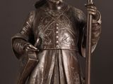 bronze statue of a man holding a staff and a book