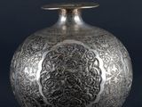 an old silver vase sitting on top of a black table