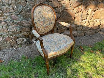 une chaise posée dans l'herbe près d'un mur de pierre