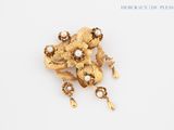 une image représentant une broche en forme de fleur en or ornée de perles, sur un fond blanc
