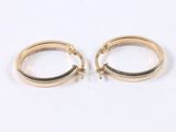 two pairs of gold hoop earrings on a white surface